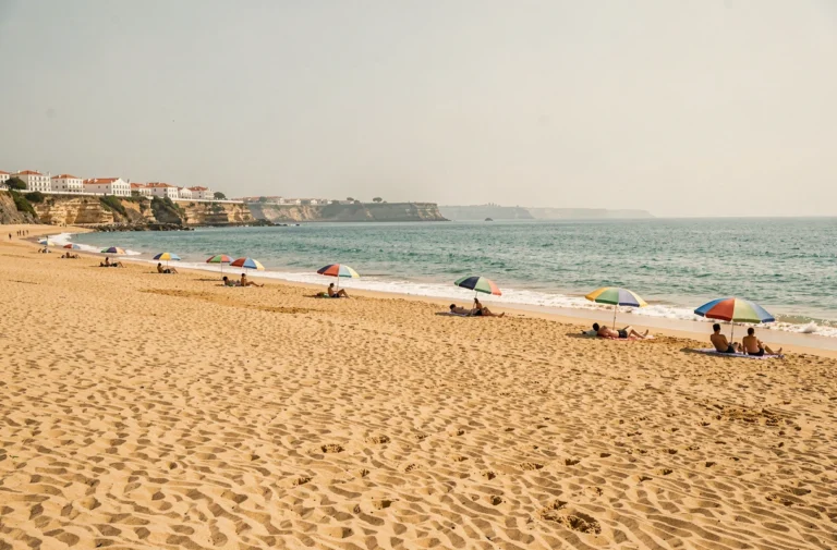 Plage dorée d'Almada au Portugal avec eaux turquoise et falaises blanches en arrière-plan