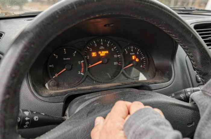 Close-up van het brandende oliewisselwaarschuwingslampje en de resetknop van de teller op het dashboard van de Renault Clio 2